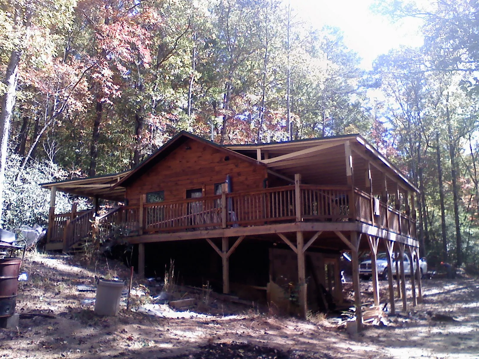 Log cabin with a wraparound porch and metal roof in the fall in Salem