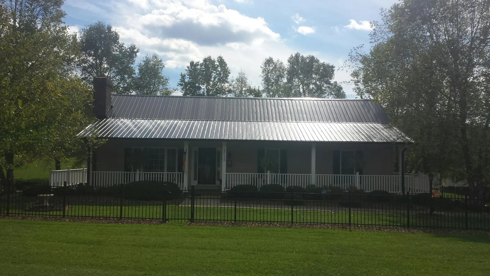 Gray metal roof on a brick ranch with a full width front porch — Gutter Guard Installation work by our crew in Salem